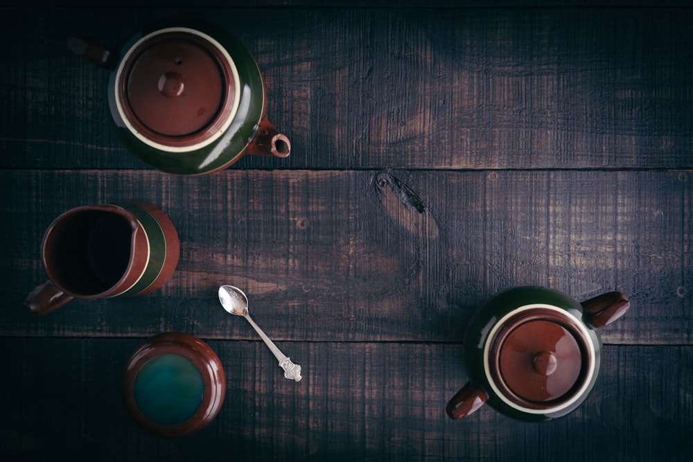 multicolored ceramic teapot and teacup on brown wooden surface