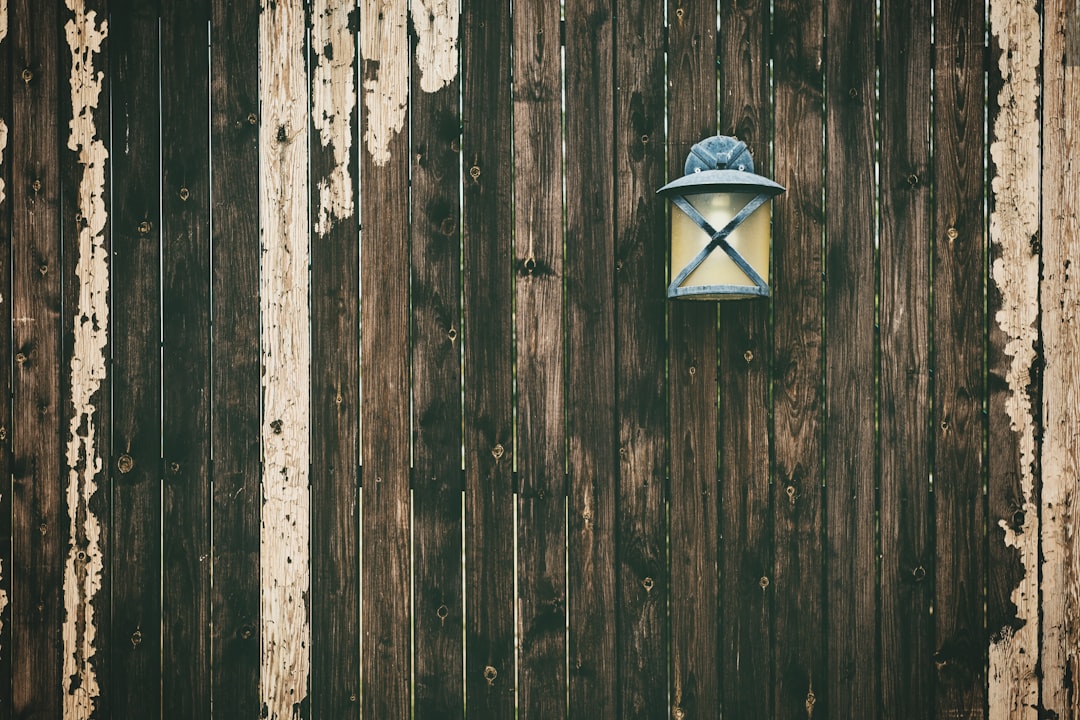 turned-on sconce lamp hanging on wooden fence