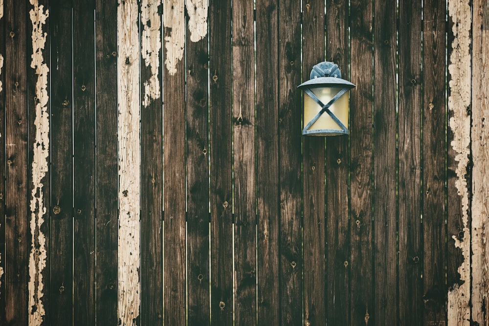 turned-on sconce lamp hanging on wooden fence