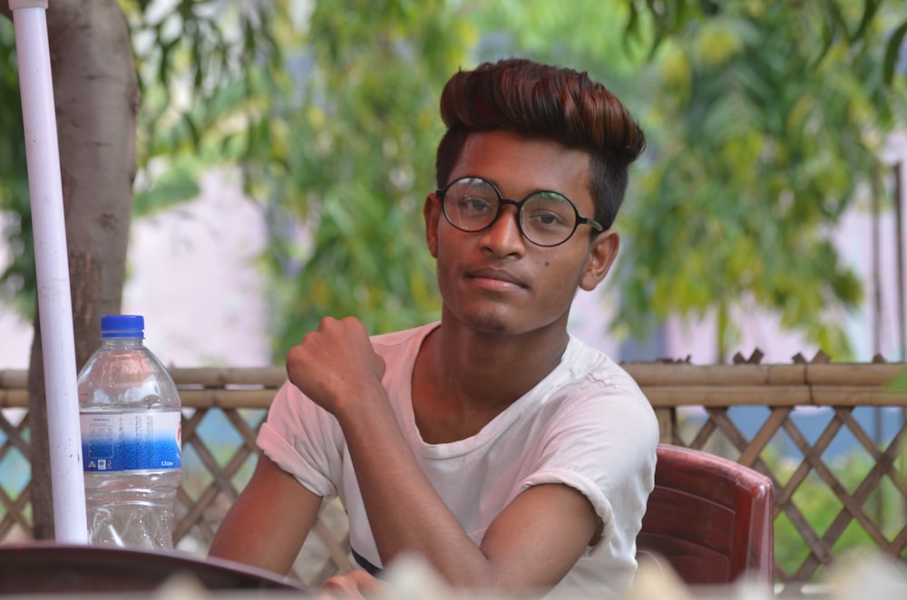 man wearing white t-shirt sitting near table