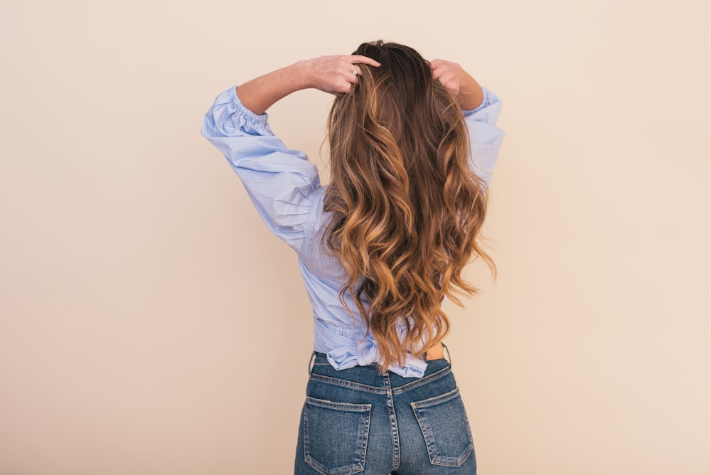 woman wearing gray dress shirt standing near white wall