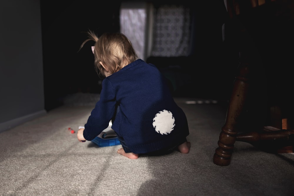 menina vestindo jaqueta azul sentada no chão