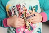 toddler holding assorted-color Crayola lot