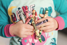 toddler holding assorted-color Crayola lot