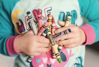 toddler holding assorted-color Crayola lot