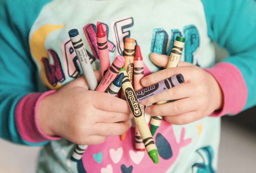 niño pequeño sosteniendo un lote de Crayola de colores variados