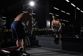 man carrying dumbbell standing in front of mirror