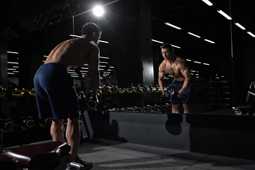 man carrying dumbbell standing in front of mirror