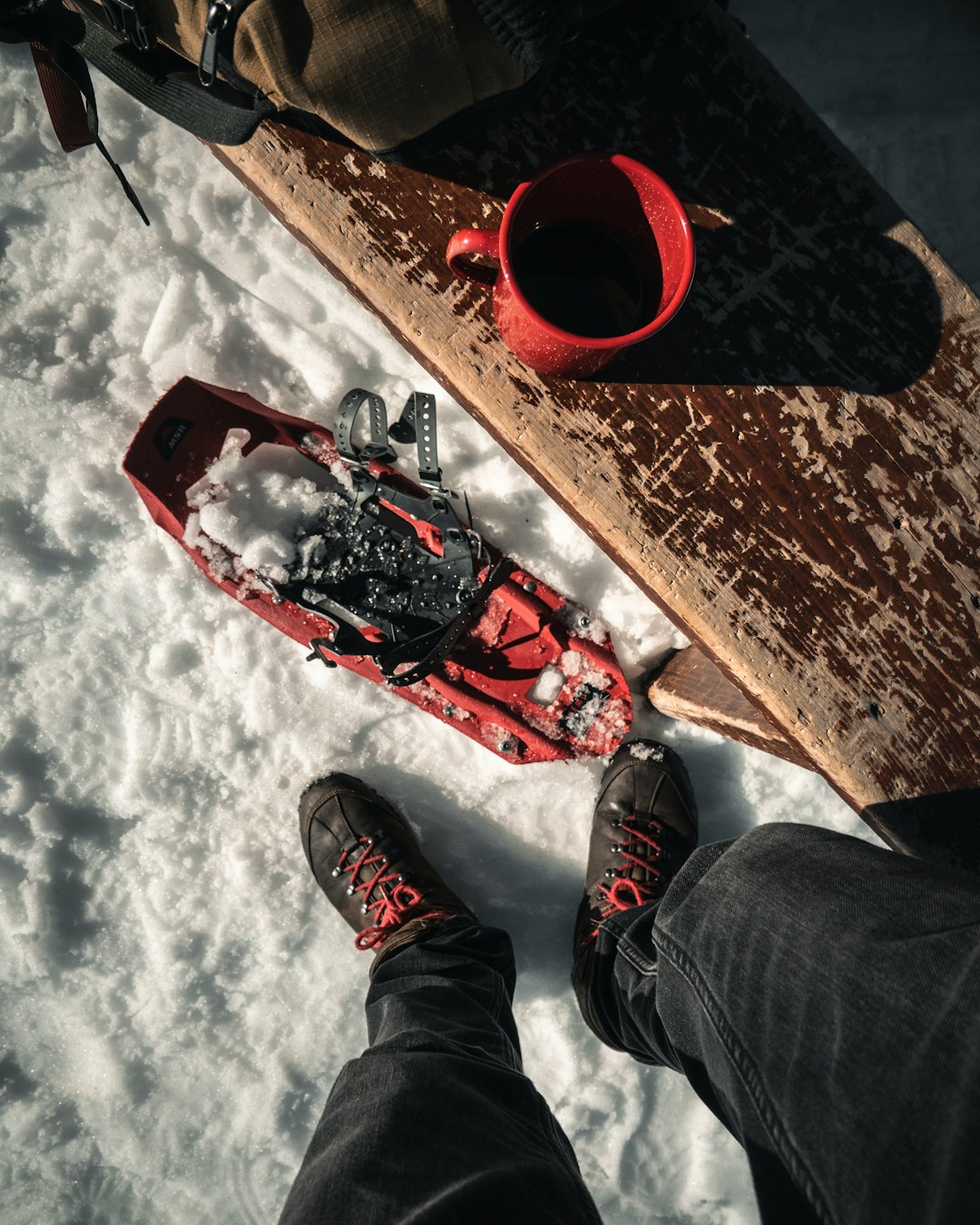 red ceramic mug on wooden bench outside snow