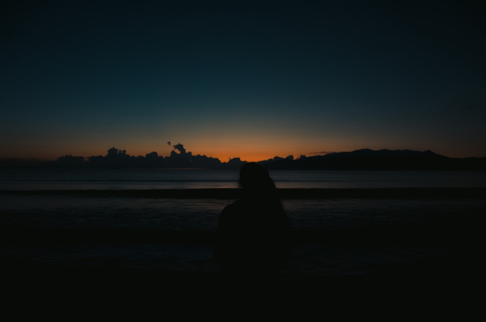 a person standing on a beach at sunset