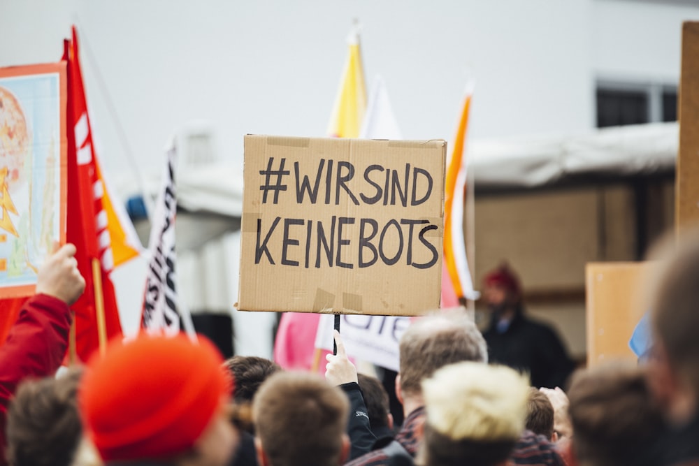Pessoa levantando placa Wirsind Keinebots