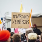 person raising wirsind keinebots signboard