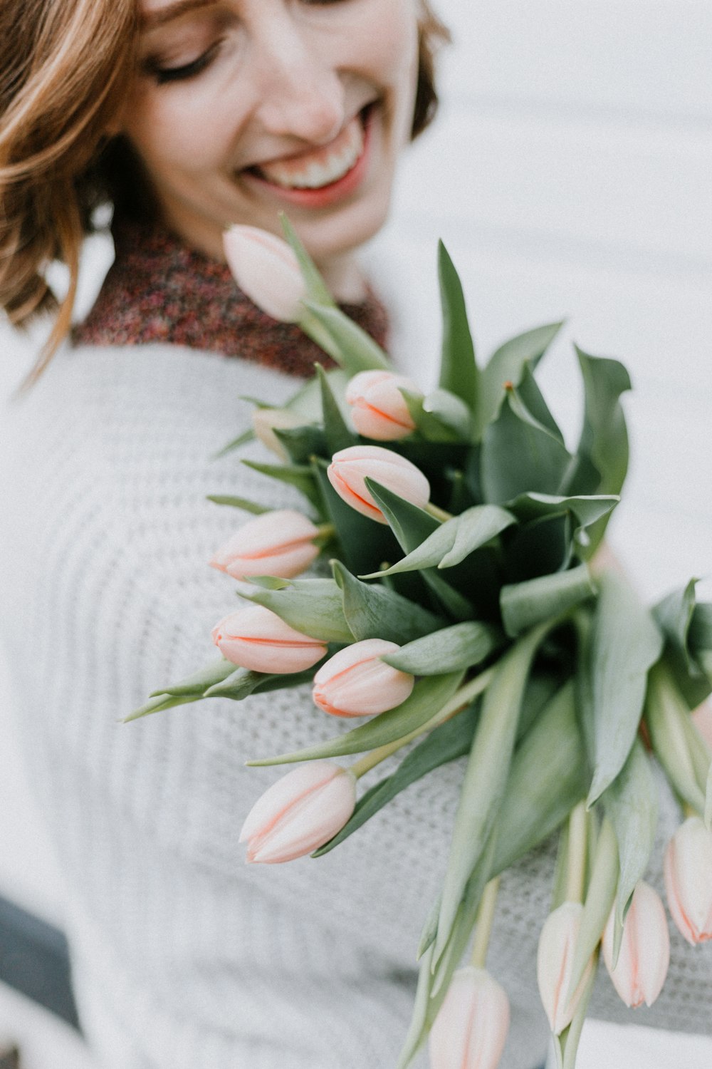 mujer agarrando ramo de flores rosas y sonriendo