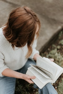 woman sitting on concrete floor reading book