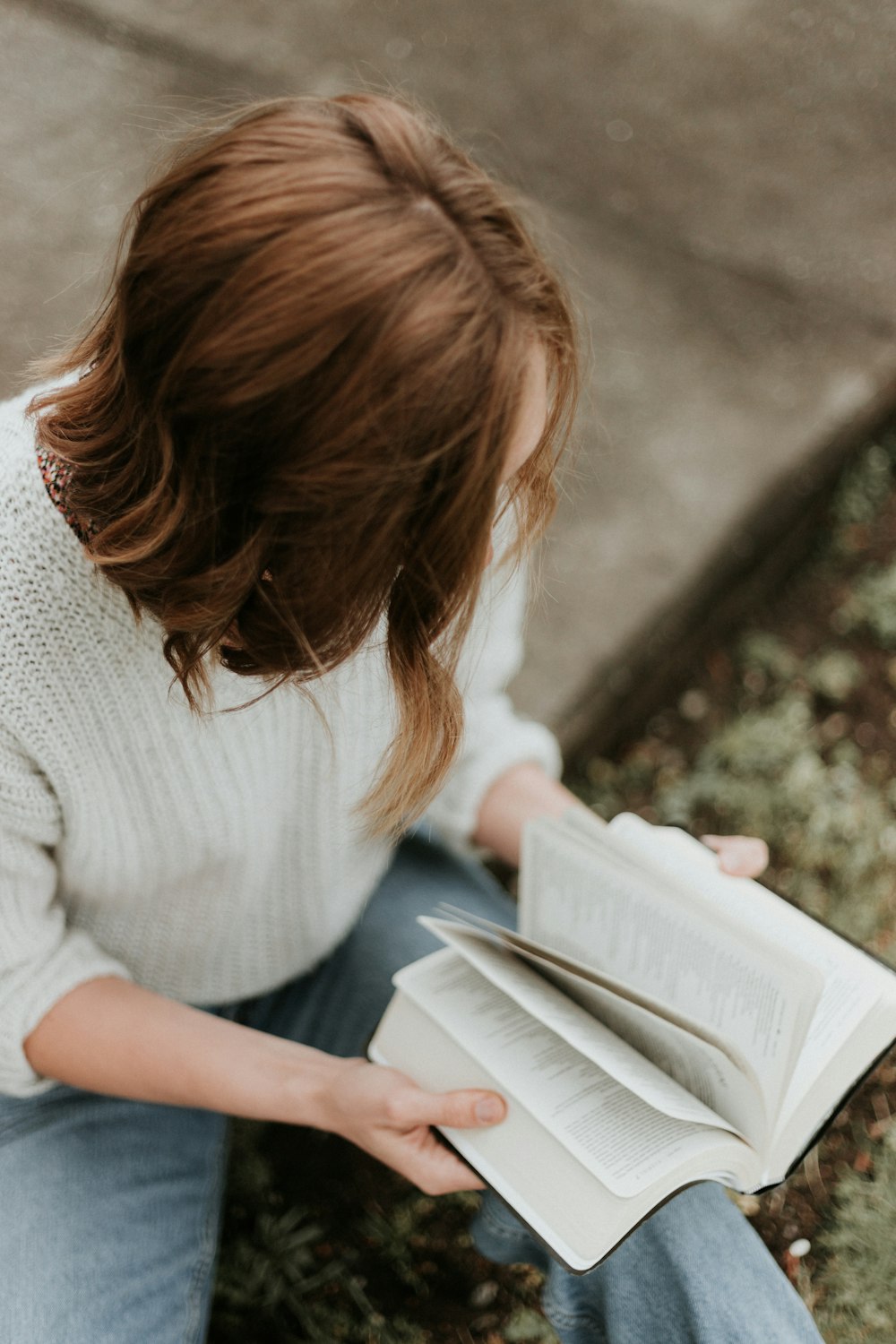 Frau sitzt auf Betonboden und liest Buch