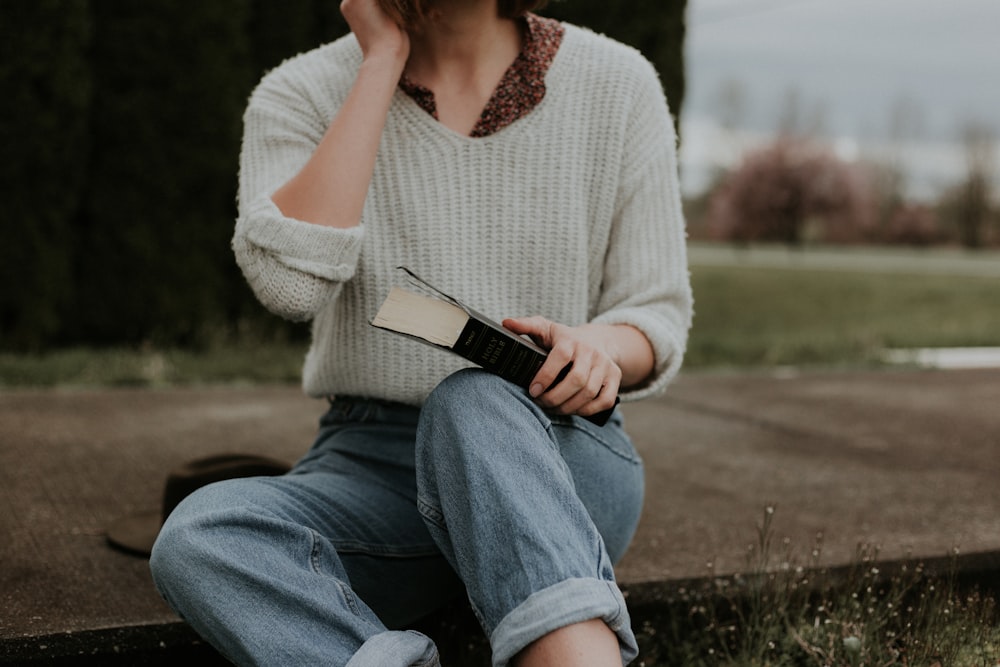 woman sitting while holding book