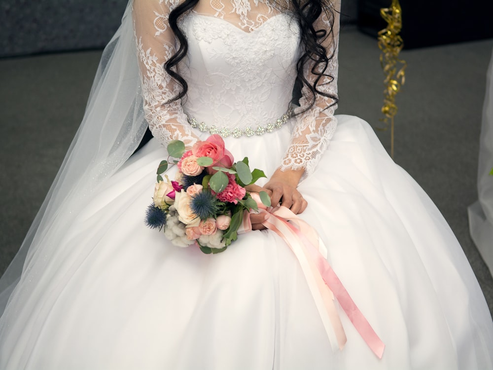 woman sitting while holding bouquet of flowers