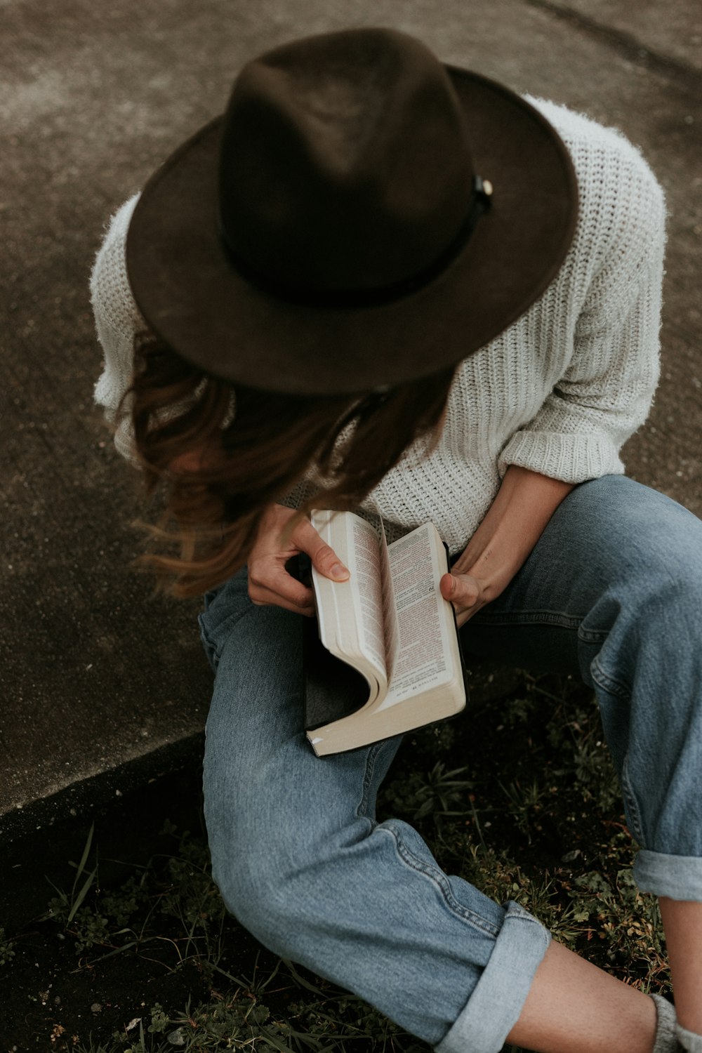 woman sitting on ground while opening book