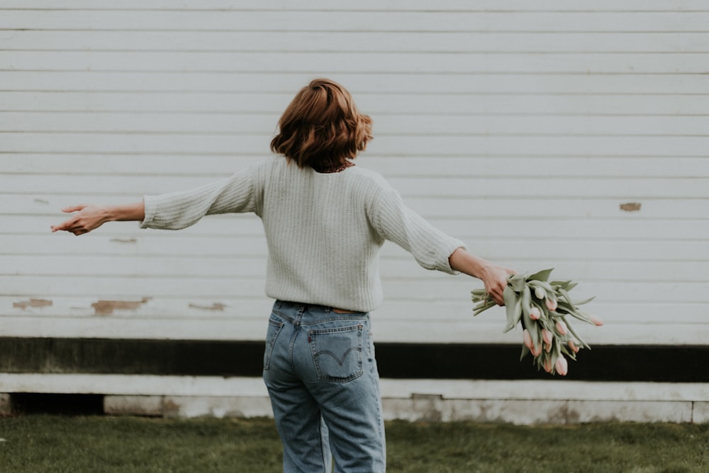 mujer sosteniendo flor de pétalos rosados