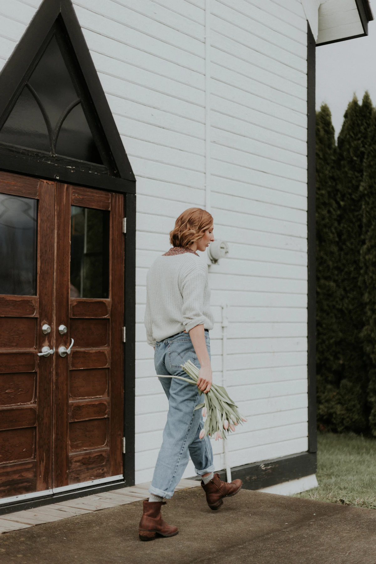 woman walking in front of closed door with flowers on hand
