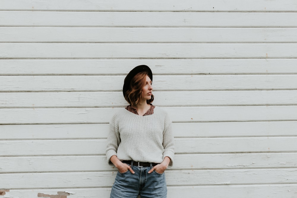 woman leaning on wall wearing gray sweater