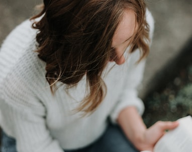 woman sitting on floor while reading book