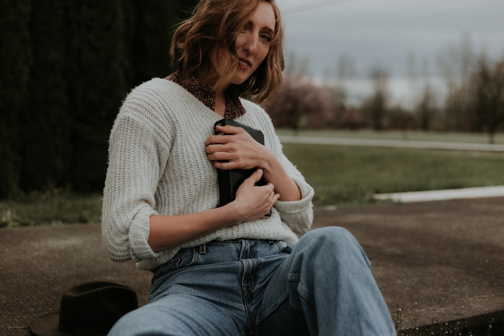 Femme portant un sac noir alors qu’elle est assise sur un sentier en béton brun