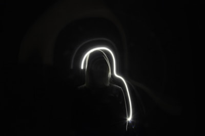 Abstract representation of light connecting a human silhouette with cosmic elements.