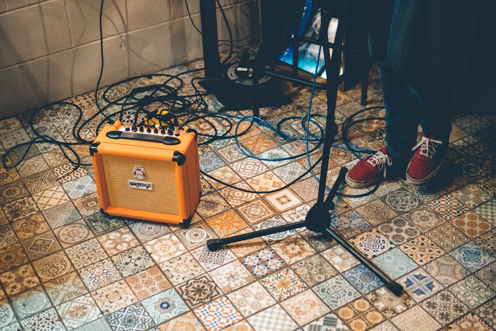 person standing near stand and orange amplifier