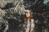 A modern woman in a flowy top paired with ethnic accessories, captured outdoors in soft sunlight.