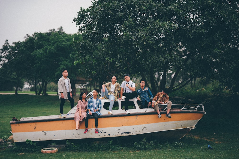 group of boys sitting on white and orange abandoned boat