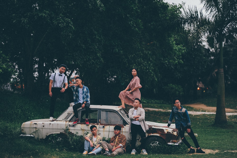 group of people taking photo beside white sedan