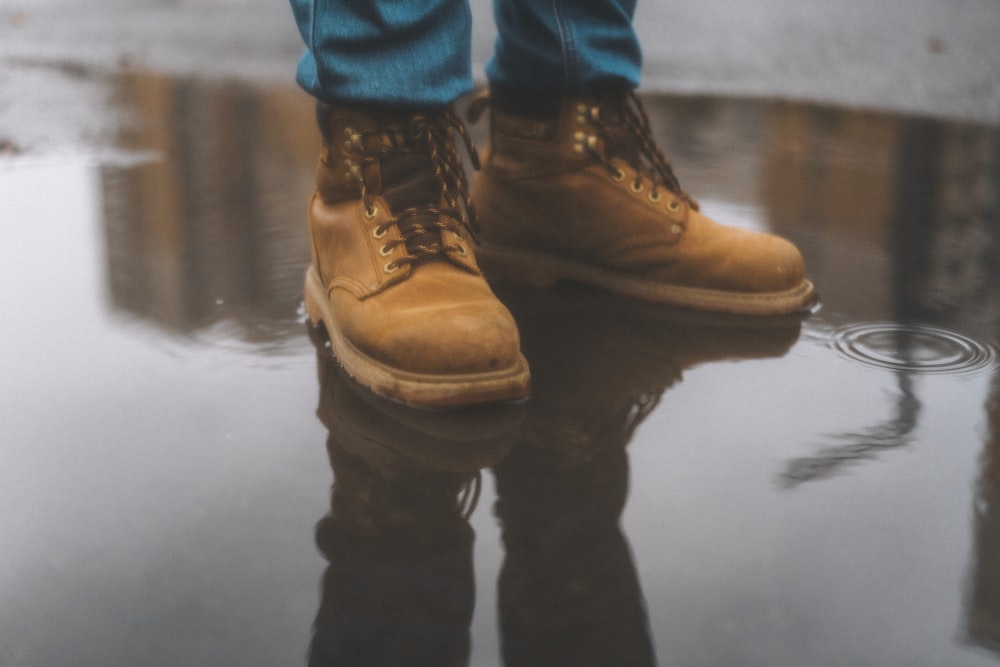 person wearing brown work boots standing on water