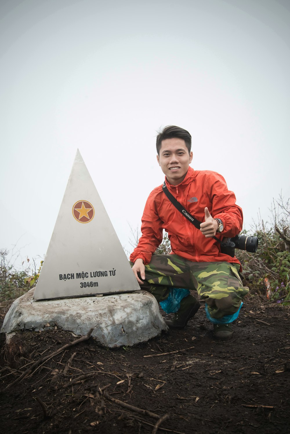 삼각형 동상 옆에 쪼그리고 앉은 남자