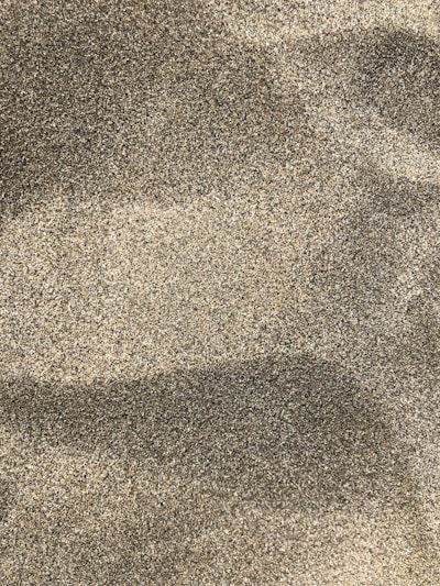 Pile of mixed fine sand blending smooth and rough particles under clear sky.