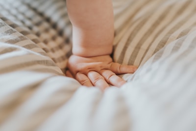 Close-up of a child’s hand touching soft, vibrant fabric of a tiny jacket.