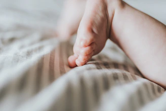 Close-up of delicate baby feet resting gently on soft fabric, bathed in warm, golden light.