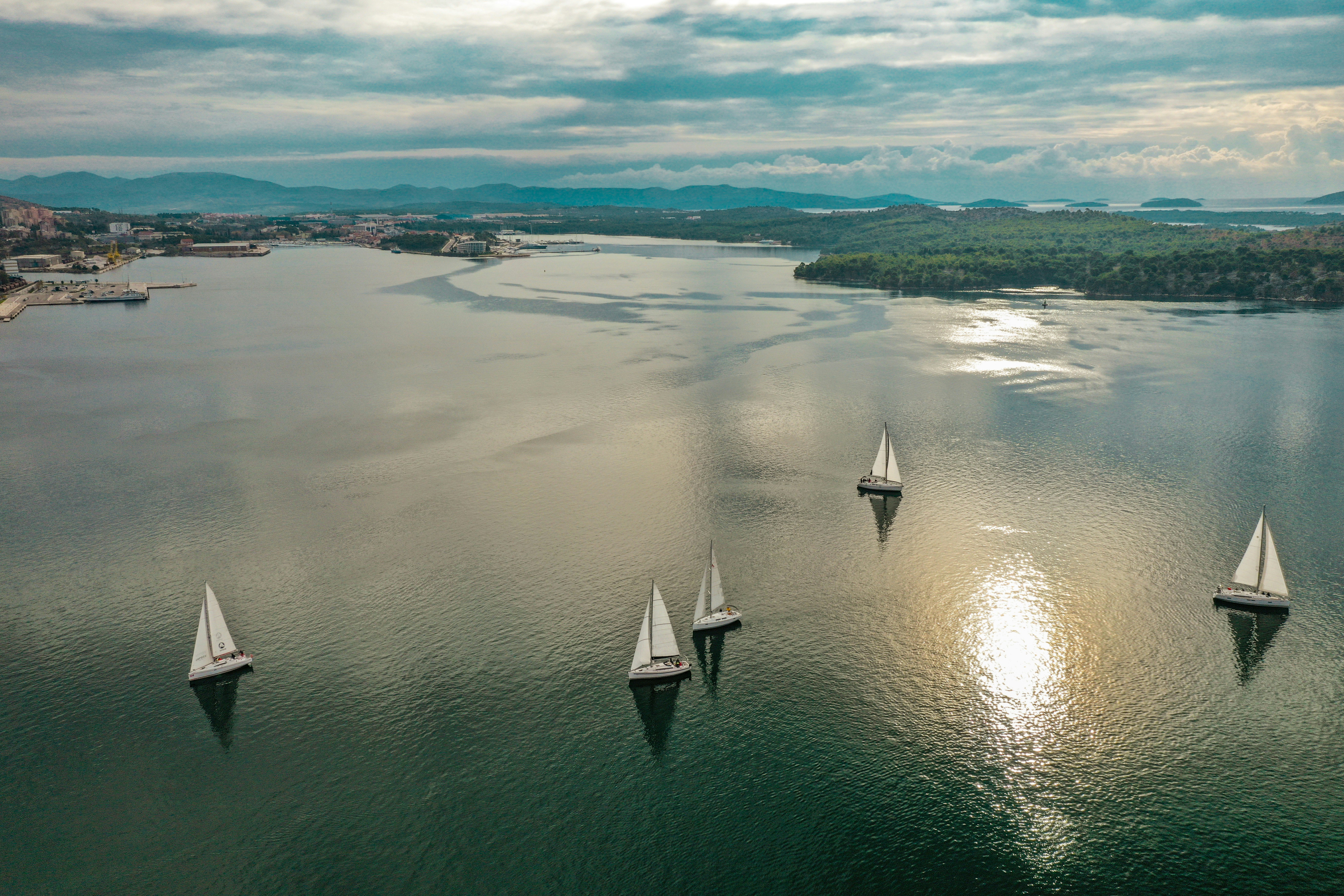 five sailboats sailing on body of water