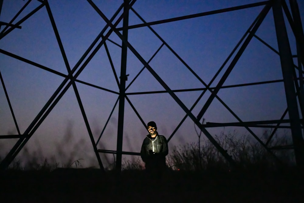 man standing under tower at night