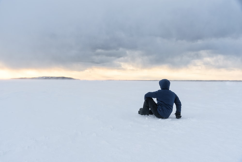 man sitting on snow field