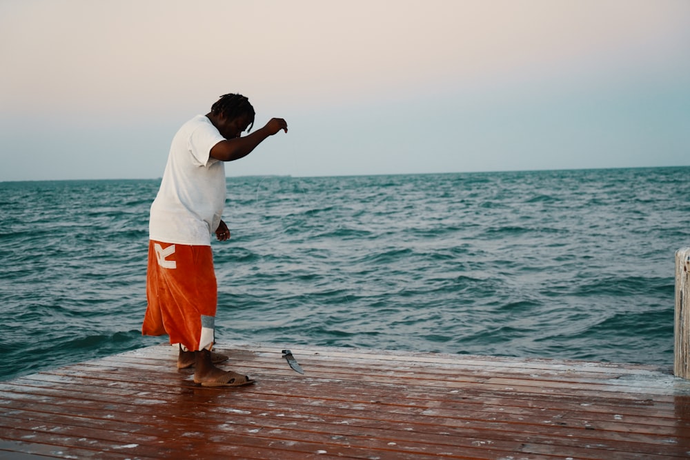 man standing on dock catching fish
