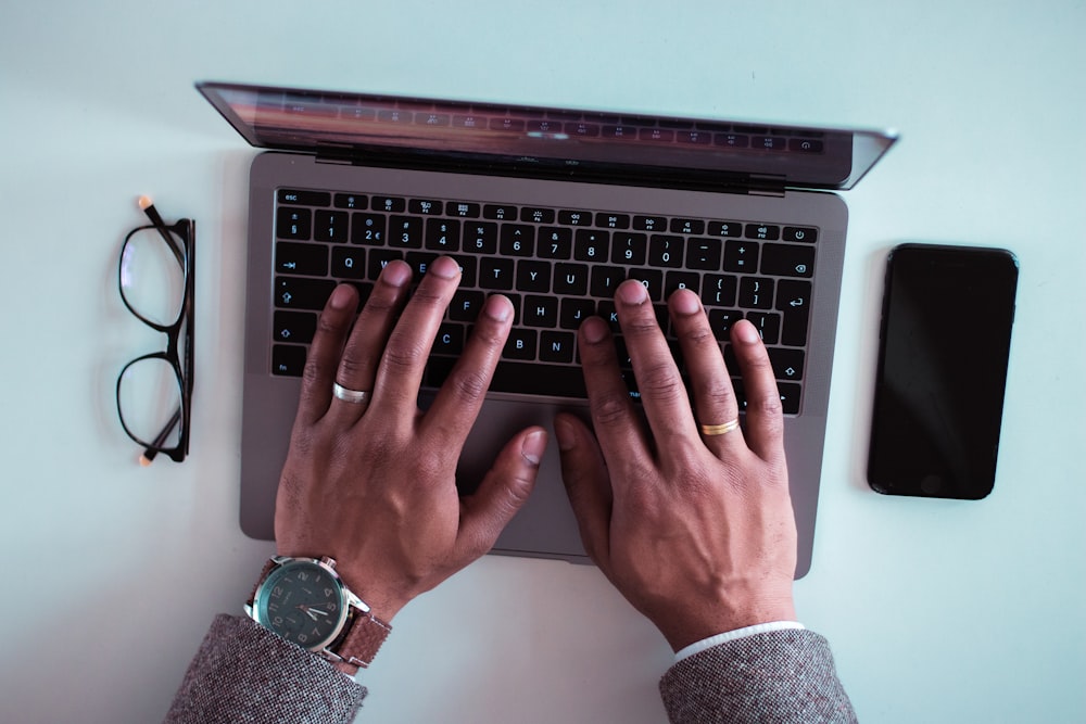 man using laptop between eyeglasses and iPhone