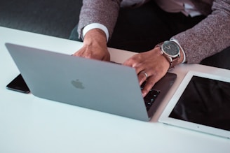 man using MacBook between iPad and iPhone