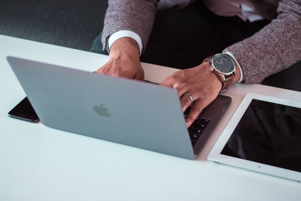 man using MacBook between iPad and iPhone