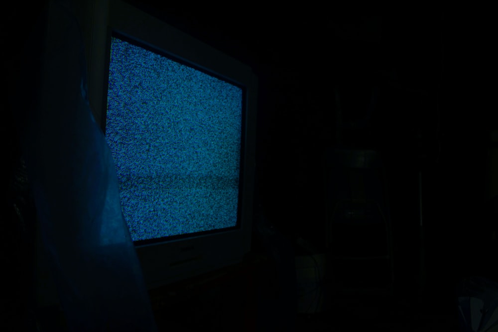 a television in a dark room with a blue screen