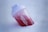 A plastic shaker bottle partially filled with red liquid is nestled at an angle in fresh, white snow. The bottle has a white lid, and text on its side reads 'ENERGY FORMULA'.