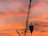 An amber-lit crane lifting materials at sunset, highlighting the company’s signature colors.