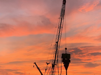 An amber-lit crane lifting materials at sunset, highlighting the company’s signature colors.