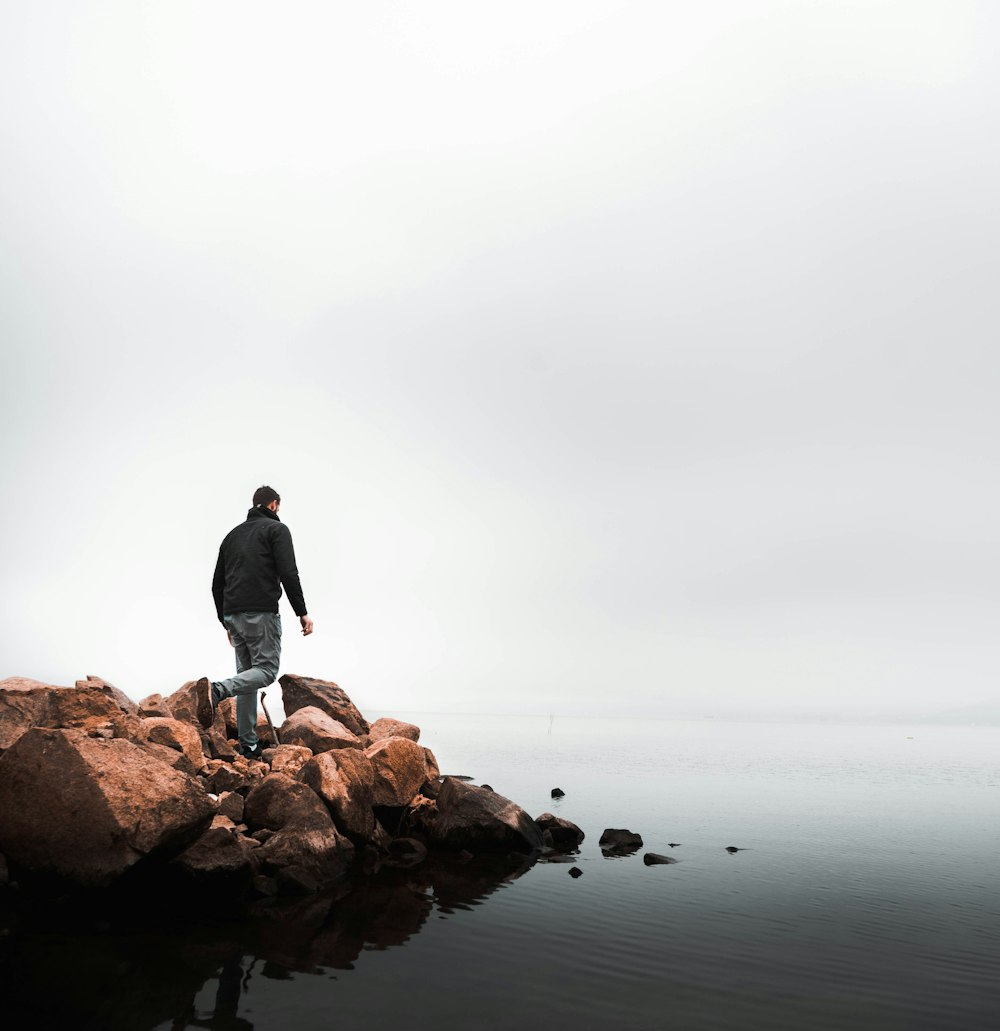 man walking on rocks beside beach