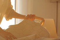 Softly lit image of a rosé nude shopping bag with the Elora logo, resting on a beige satin surface.